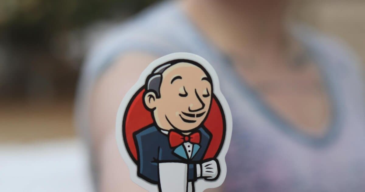 Hand holding a Jenkins sticker outdoors, blurred background for focus effect.