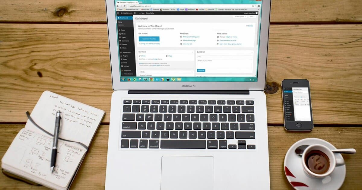 A cozy home office scene with a laptop, notebook, smartphone, and coffee, perfect for productivity.