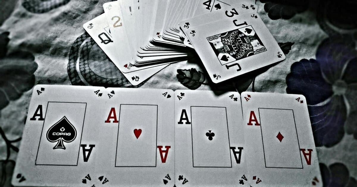 A close-up view of playing cards showing four aces, symbolizing a winning hand in poker.