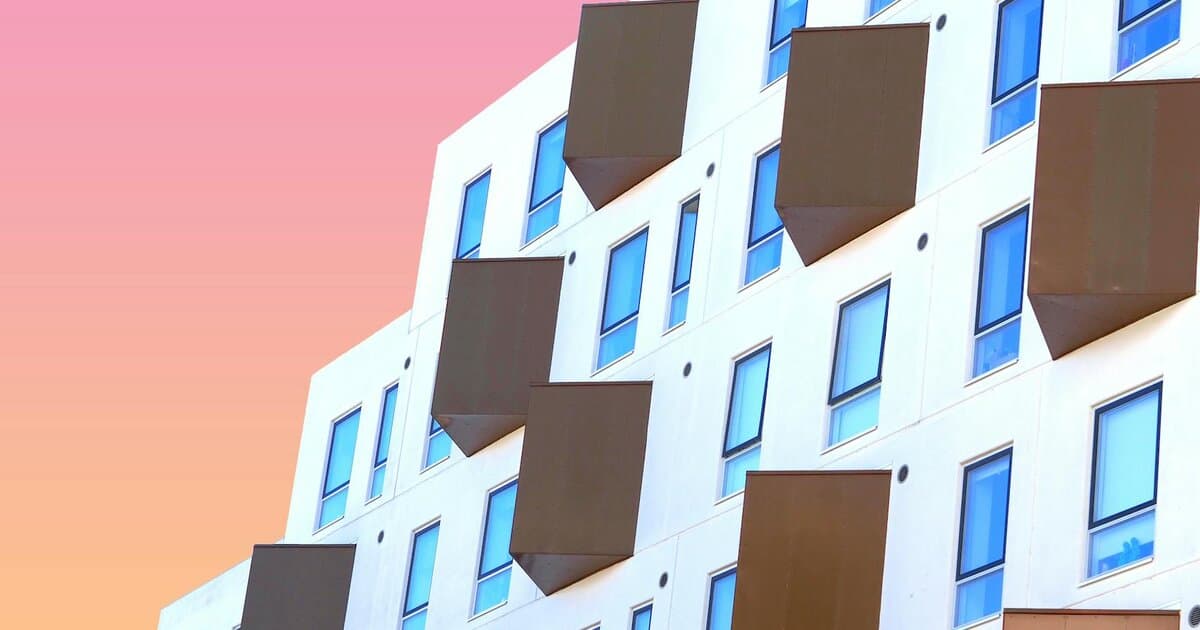 Contemporary building facade with unique windows in Odense, Denmark, under a pastel sky.