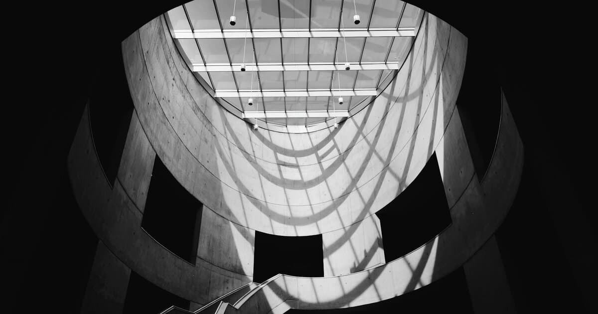 Dramatic black and white photo of a modern architectural staircase with skylight.