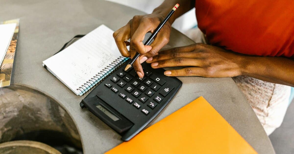 An African American woman using a calculator and notepad for budgeting.