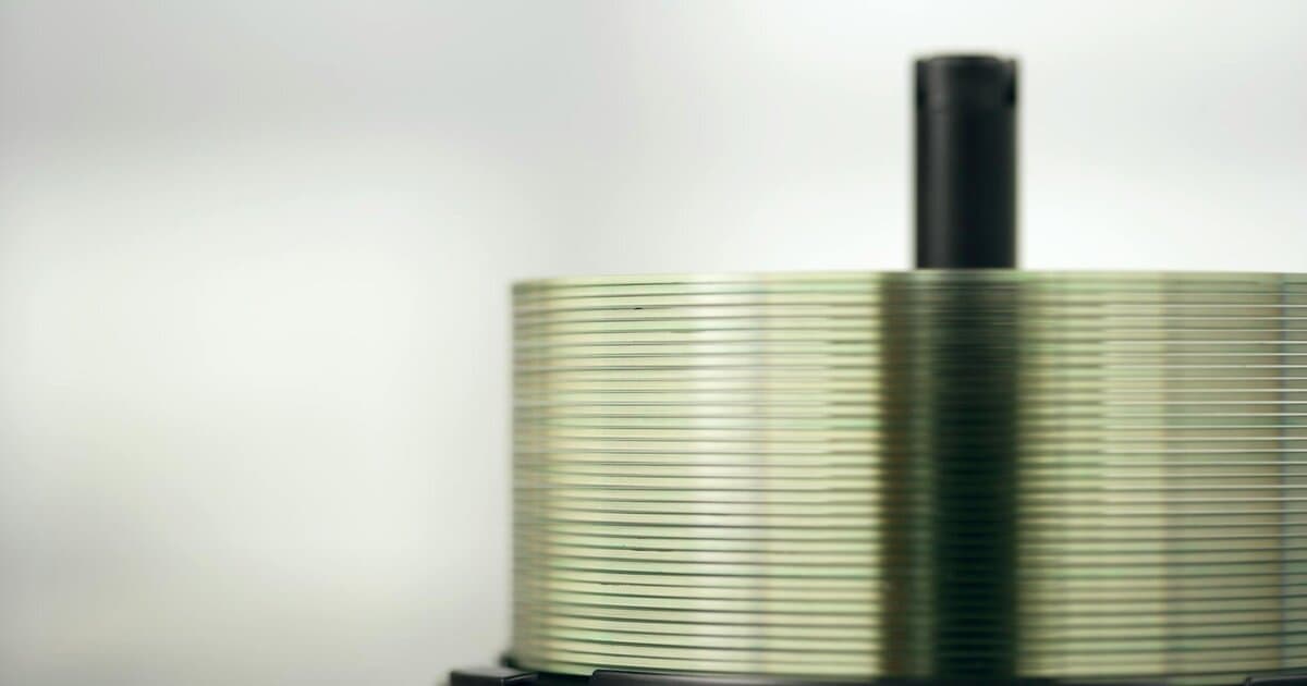 Detailed view of a stack of compact discs on a spindle, highlighting their reflective surfaces.