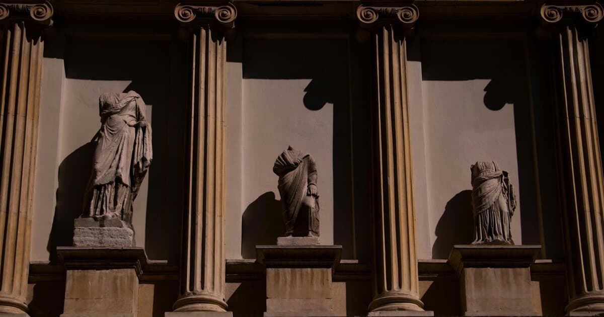 Three headless statues adorn a neoclassical facade in Istanbul, Türkiye, highlighting ancient art.