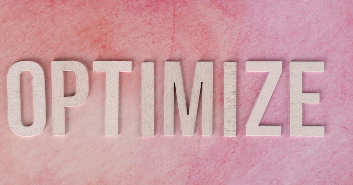 Creative display of the word 'OPTIMIZE' on a pink textured surface.