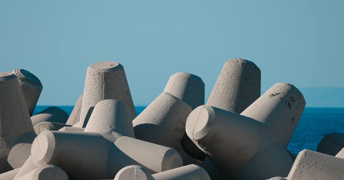 Photograph of concrete tetrapods on a seawall with a clear blue ocean backdrop under a sunny sky.