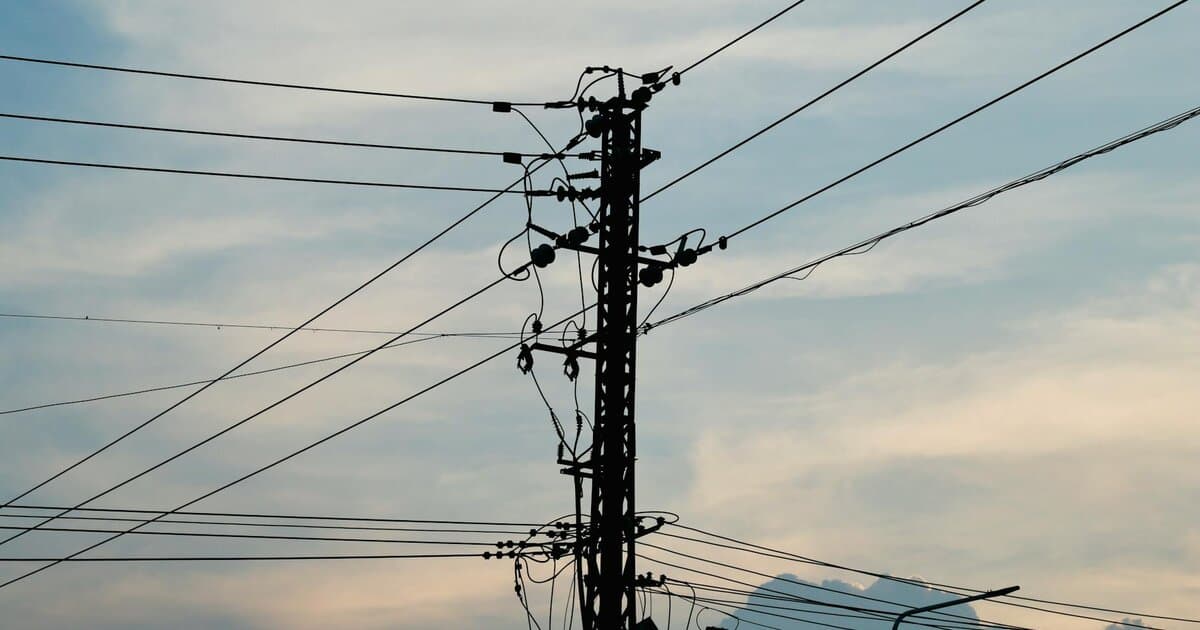 Silhouette of power lines and pole against a vibrant sunset sky.