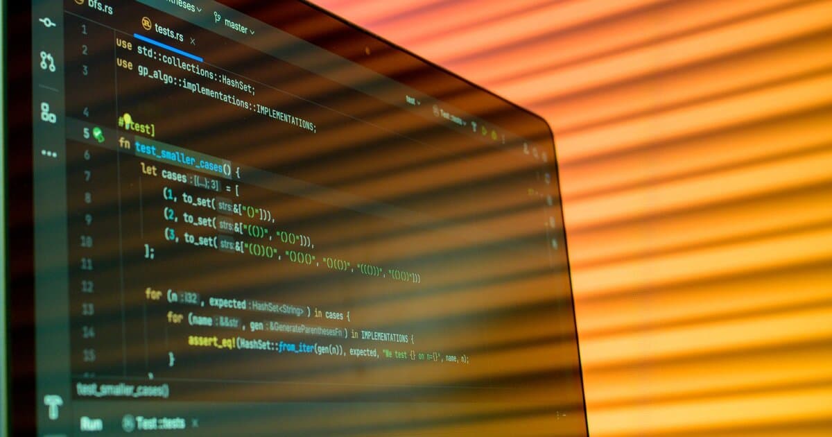 Blurry close-up of a computer screen displaying code with orange lighting.