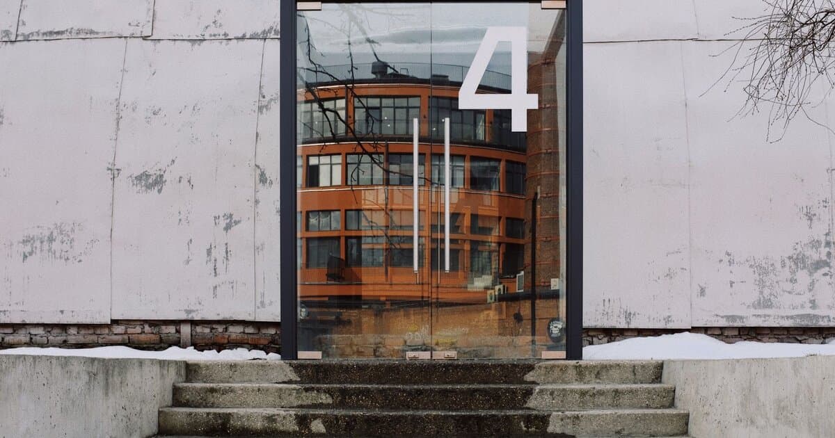 From below of modern building facade with number four on glass entrance door and stairs