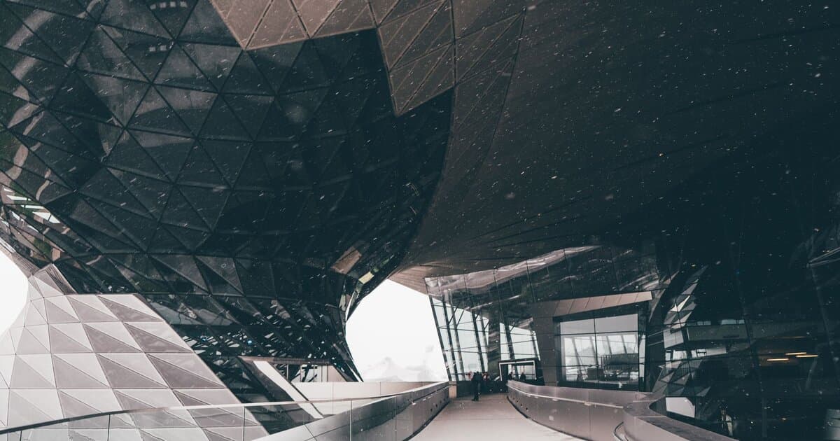 Futuristic architectural design with snow in Munich, showcasing glass and geometric features.
