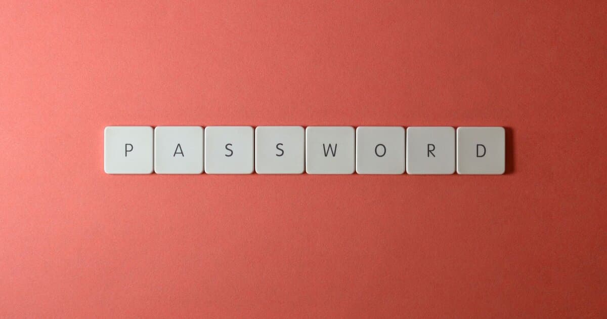 Focus on password security with white keyboard tiles spelling 'PASSWORD' on a coral background.